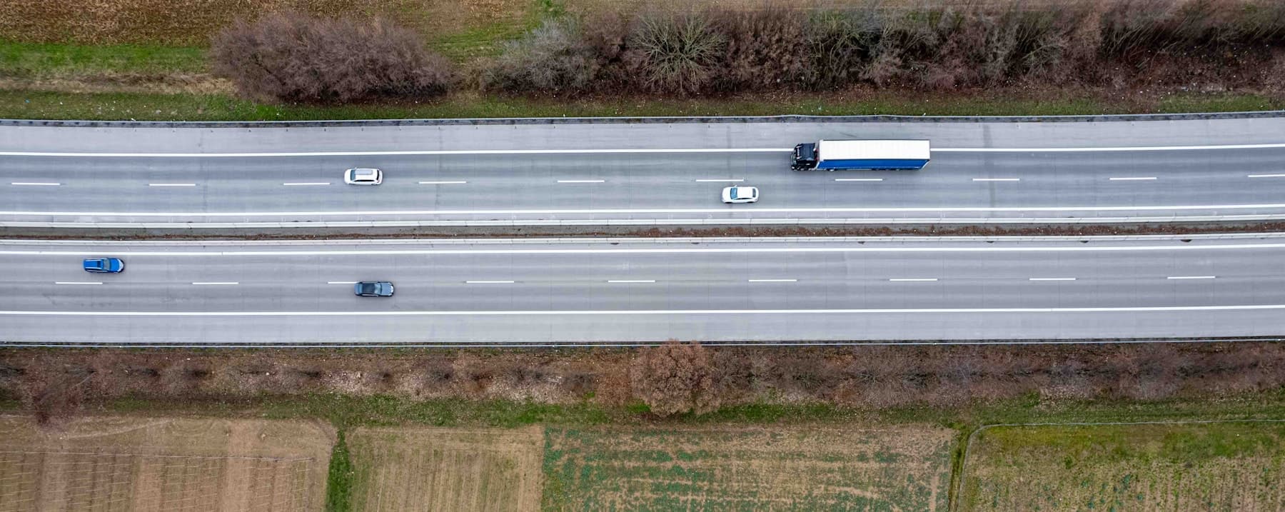 Overhead view of a divided highway with a tractor-trailer travelling in the outside lane.